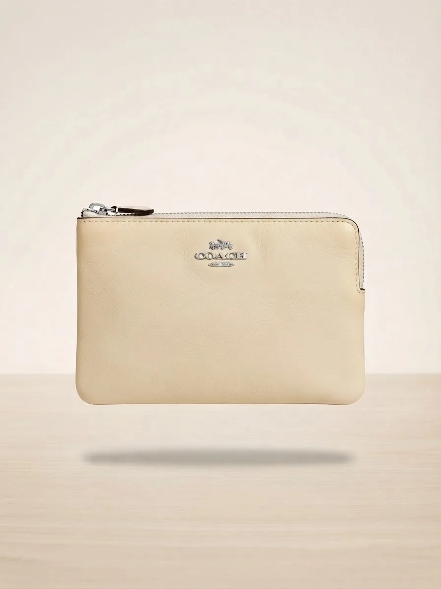 Cartera de Mano (Wristlet) de La Marca Coach, Modelo 'Corner Zip', en Un Elegante Color Beige Claro O Crema.