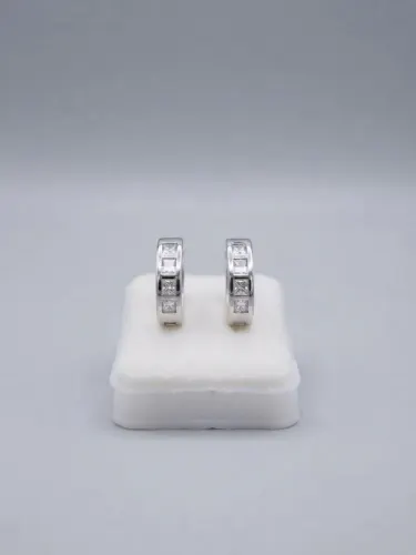 Un par de aretes tipo argolla (huggies) de color plateado